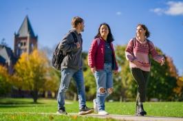 三个学生走在校园里，背景是汤普森大厅